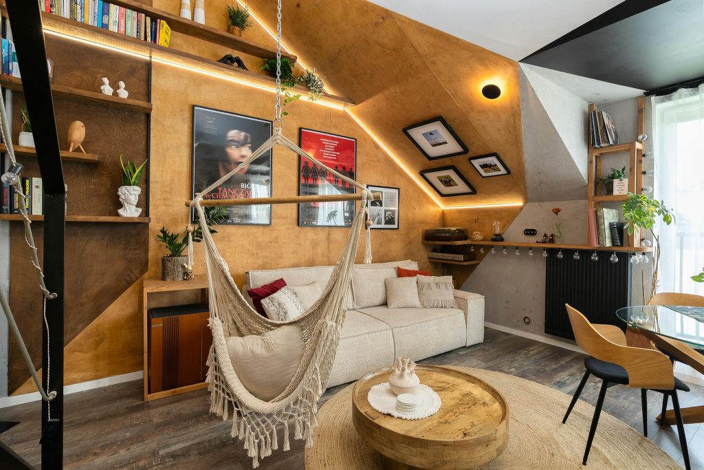 Stylish living room featuring a hammock, wooden furniture, and indoor plants, creating a cozy atmosphere.