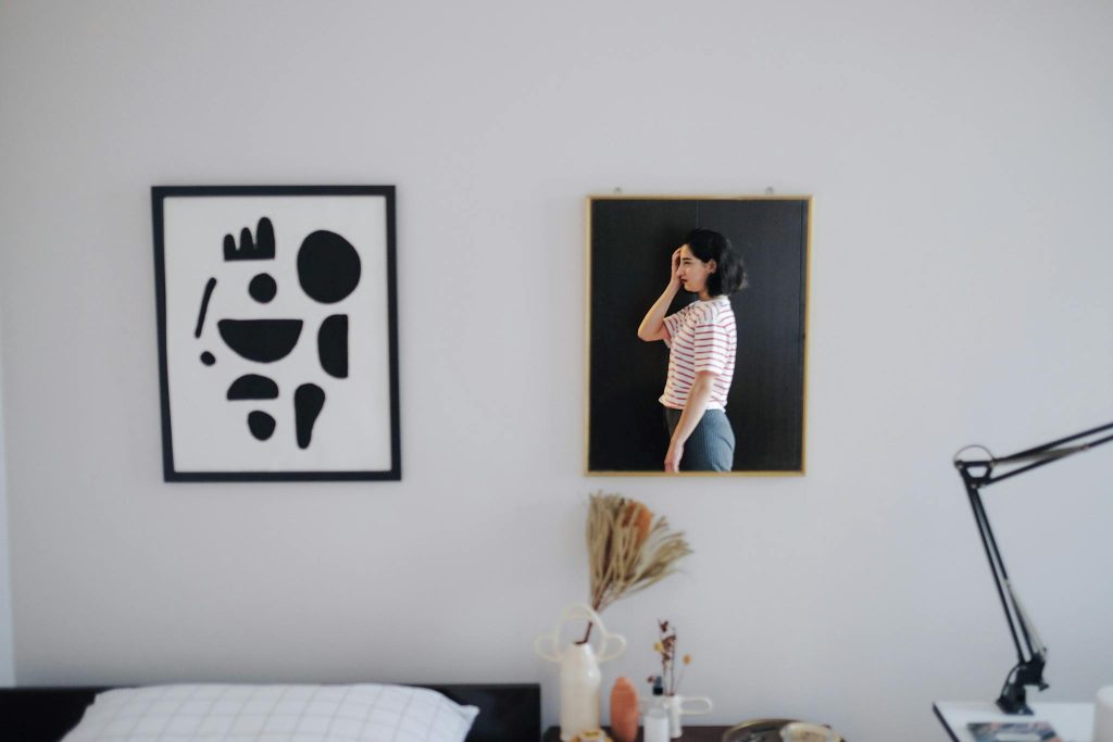 Stylish room interior featuring abstract art and a reflective mirror with a woman's portrait.